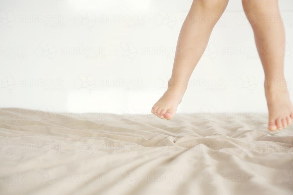 Feet of Child Jumping On The Bed - Australian Stock Image