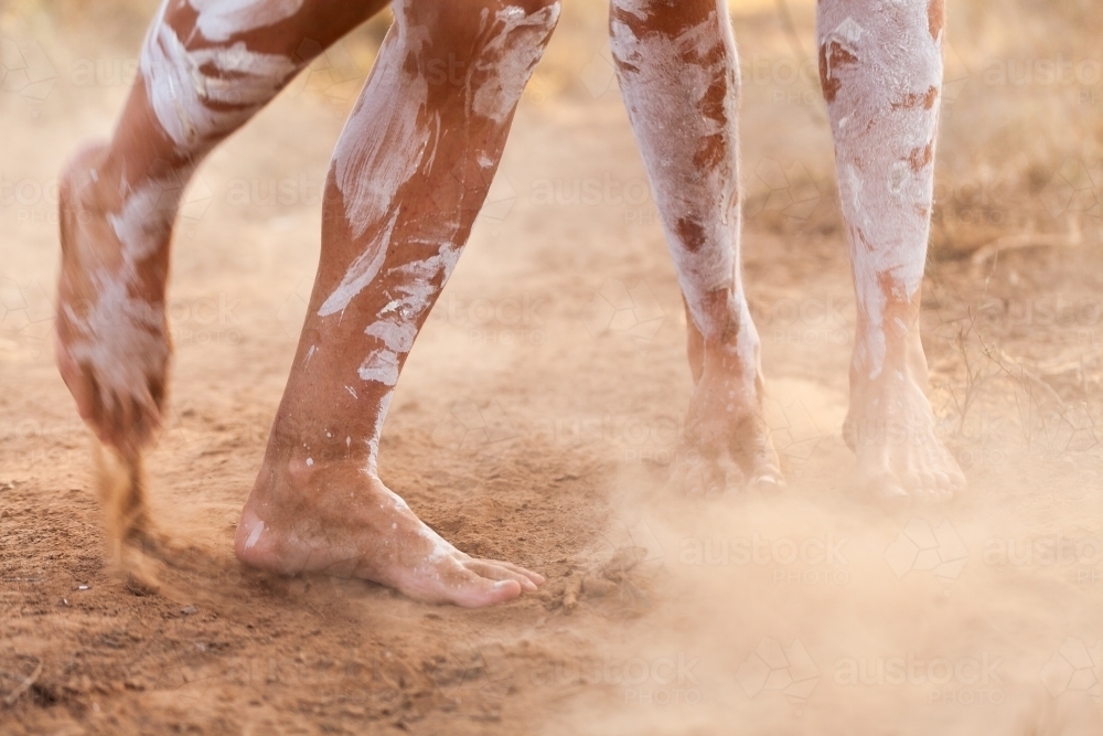 Feet of First nations people dancing in oka paint to tell the story kicking up dust - Australian Stock Image