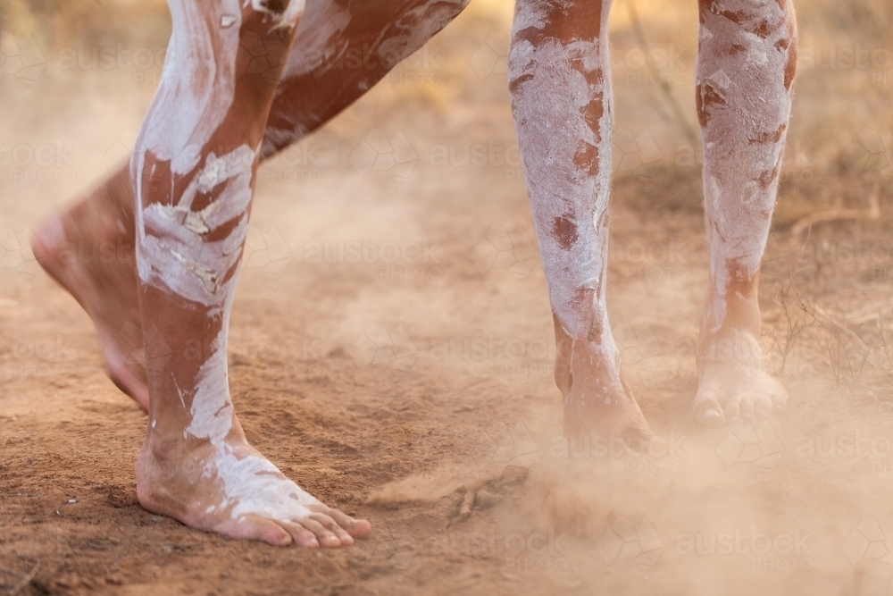 Feet of First nations people dancing in oka paint to tell the story kicking up dust - Australian Stock Image