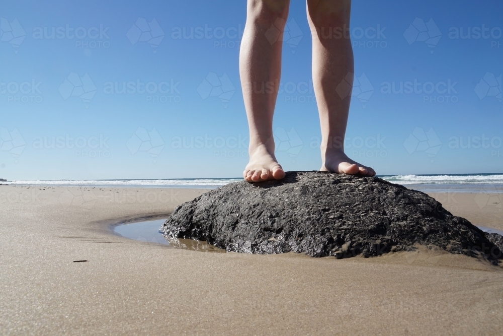 Feet standing on rock at beach - Australian Stock Image