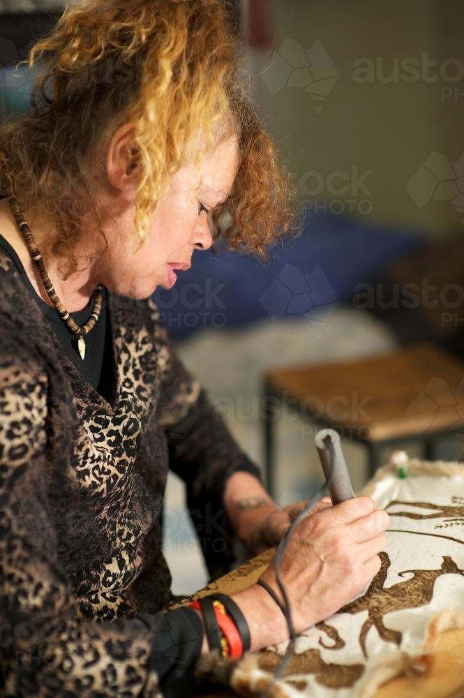 Female Aboriginal Artist at Work on Possum Skin - Australian Stock Image