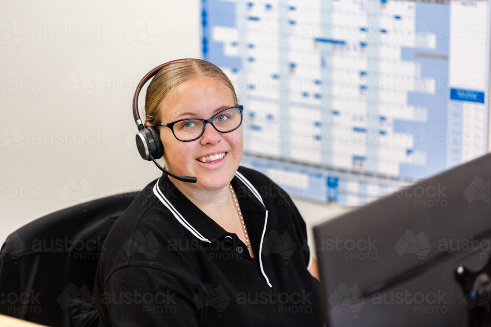 female administrate staff lady sitting by computer at front desk office - Australian Stock Image