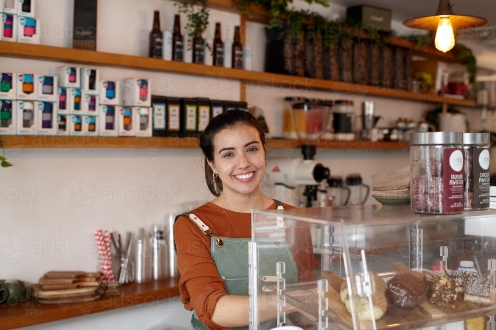Female barista smiling whilst working inside coffee shop - Australian Stock Image