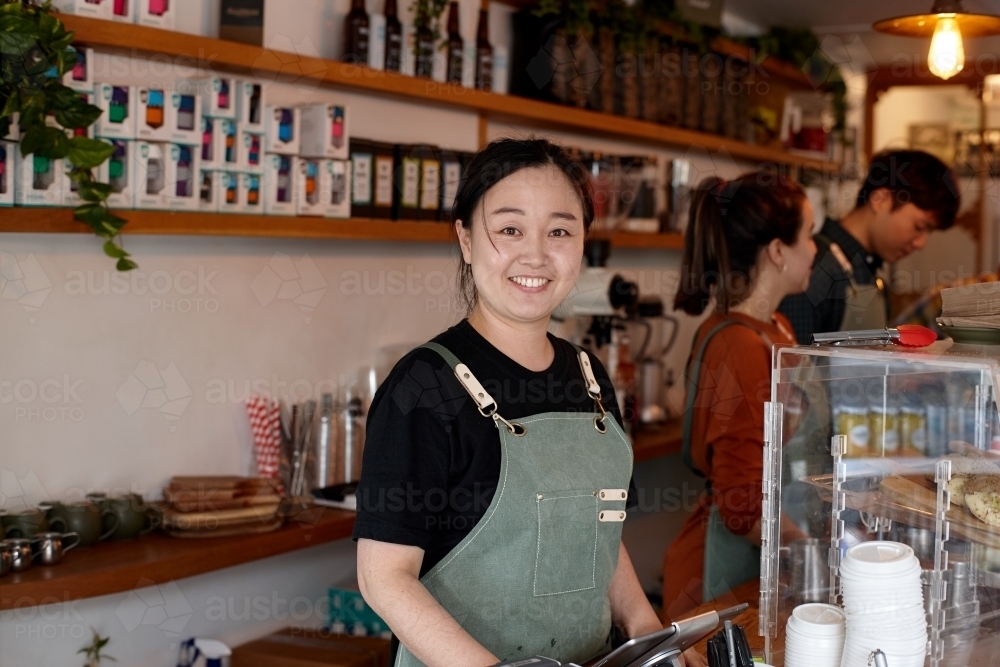 Female barista smiling whilst working inside coffee shop - Australian Stock Image