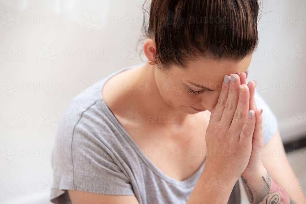 female bow hands to third eye yoga meditation pose in studio - Australian Stock Image