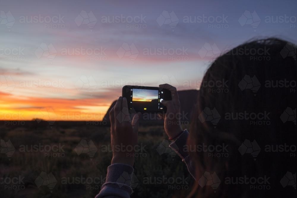 Female capturing a photo of sunrise at Uluru-Kata Tjuta National Park - Australian Stock Image
