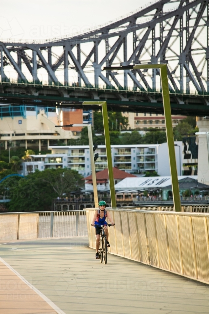 Female Cyclist Riding with Story Bridge Behind - Australian Stock Image