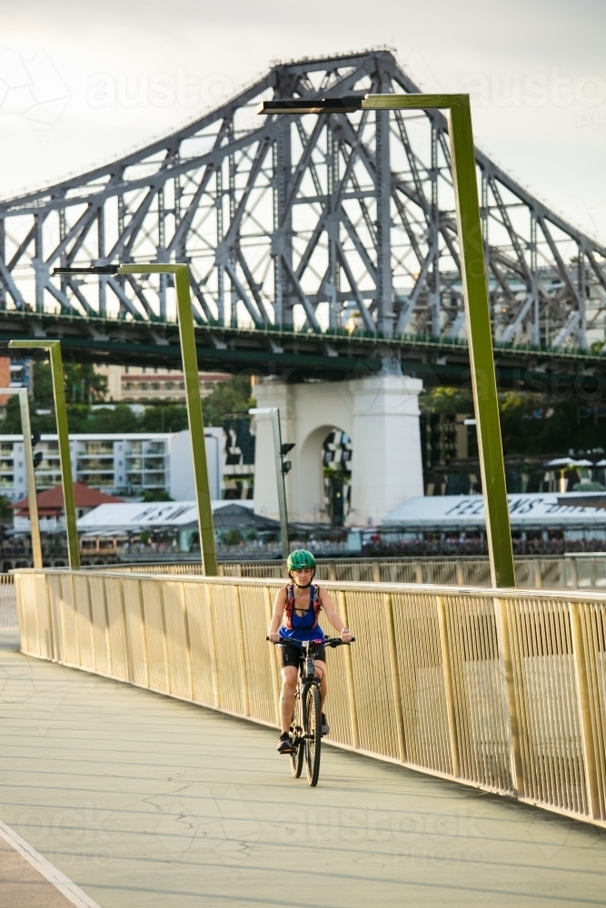 Female Cyclist Riding with Story Bridge Behind - Australian Stock Image
