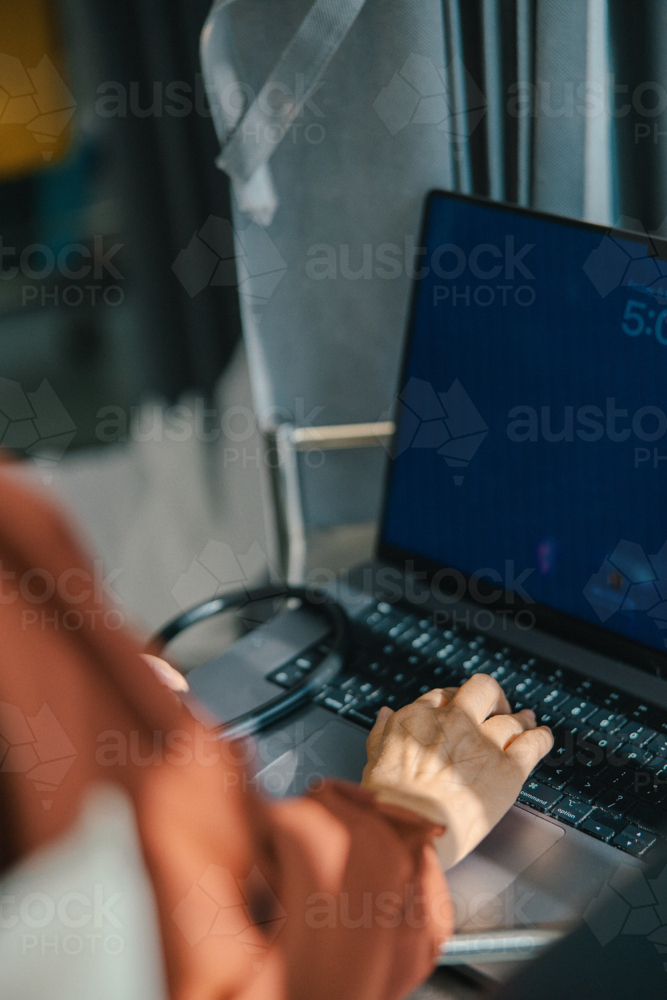 Female doctor typing on the laptop for documentation - Australian Stock Image