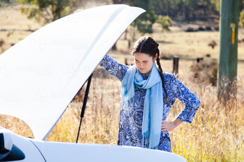 Female driver looking at engine on roadside - Australian Stock Image