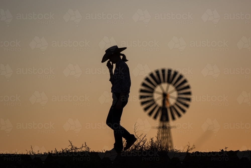 Female farmer and windmill in silhouette - Australian Stock Image