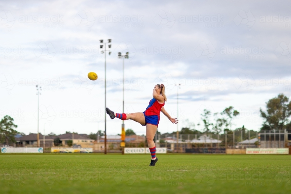 female football player kicking the ball on a football oval - Australian Stock Image