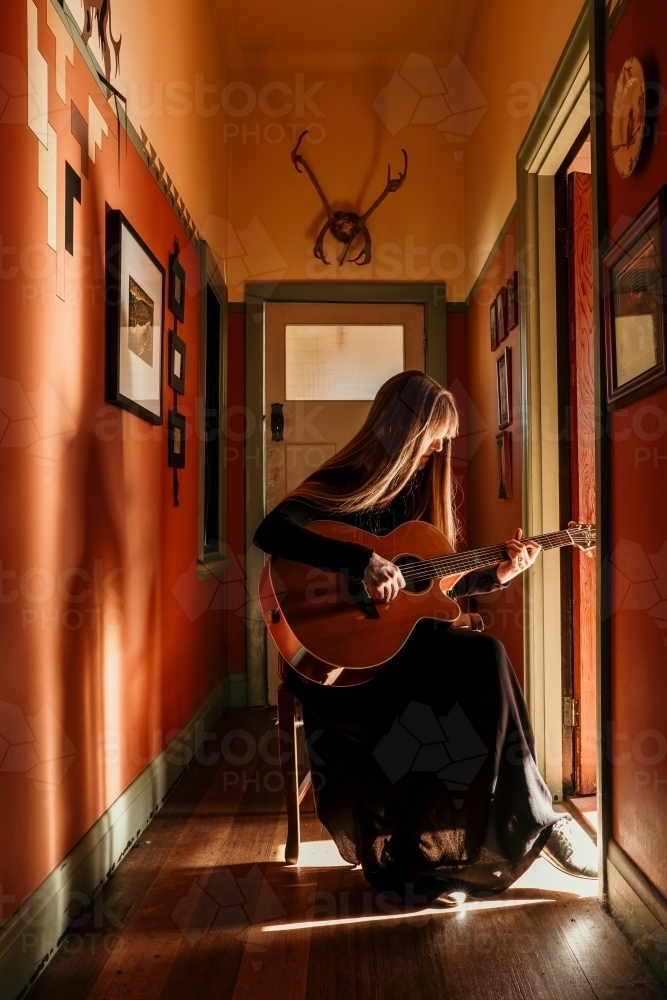 Female guitarist plays in beautiful light. - Australian Stock Image