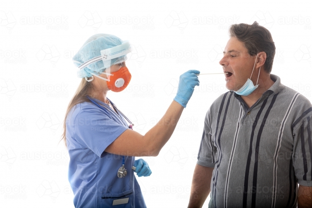Female healthcare worker swabs a man for infectious disease such as SARS or COVID-19 or influenza - Australian Stock Image