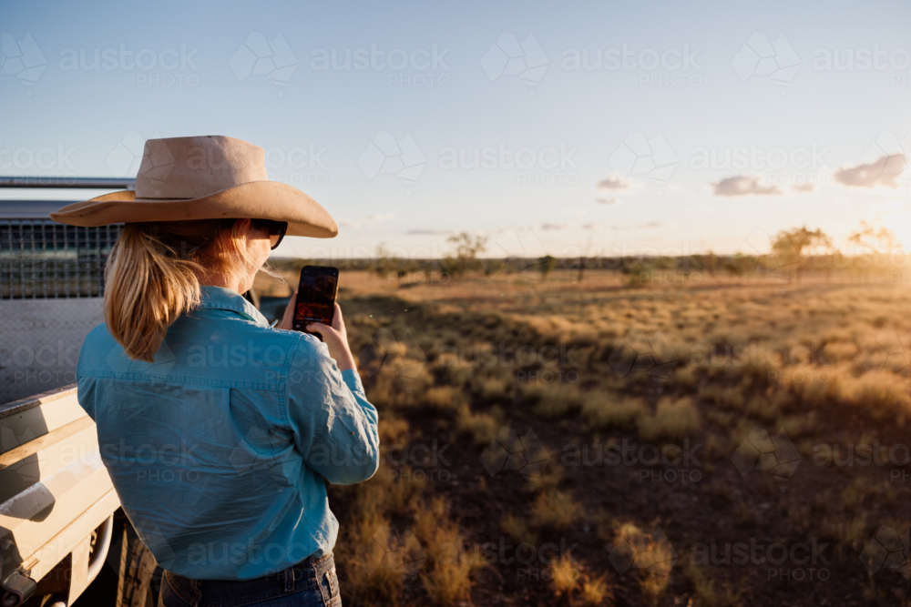 Female holding a phone using technology on the farm - Australian Stock Image