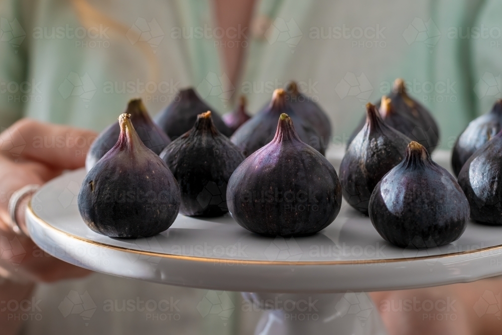 Female holding a plate of fresh figs - Australian Stock Image