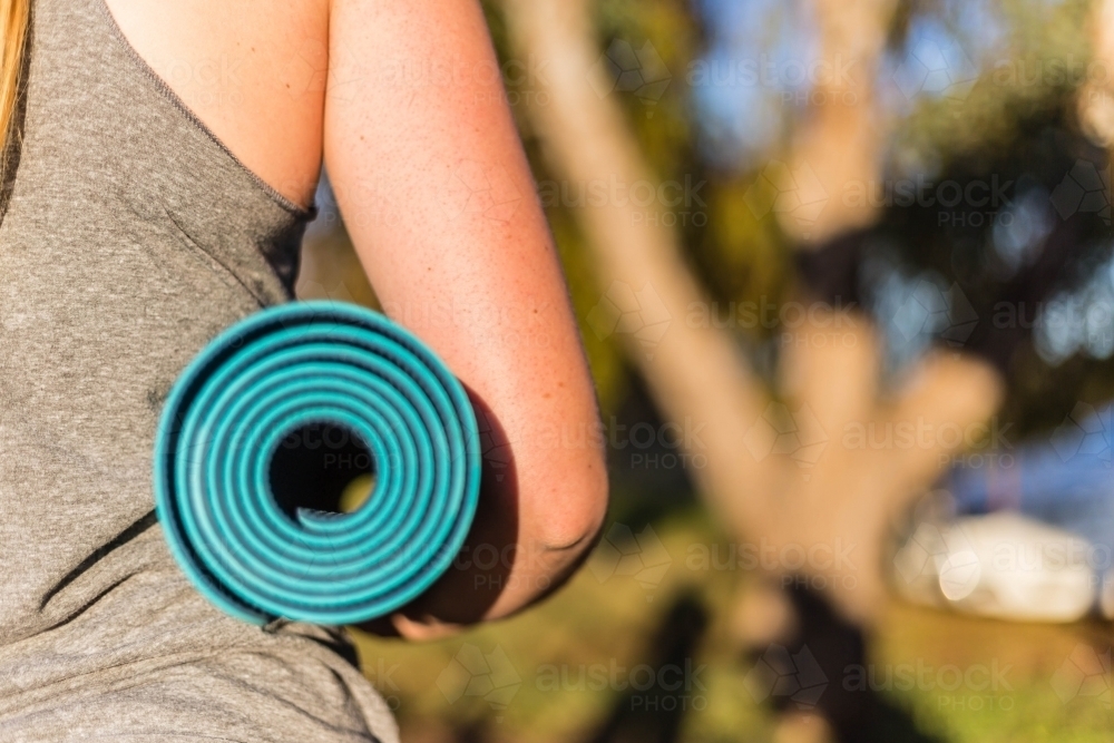 Female holding yoga mat outdoors - Australian Stock Image
