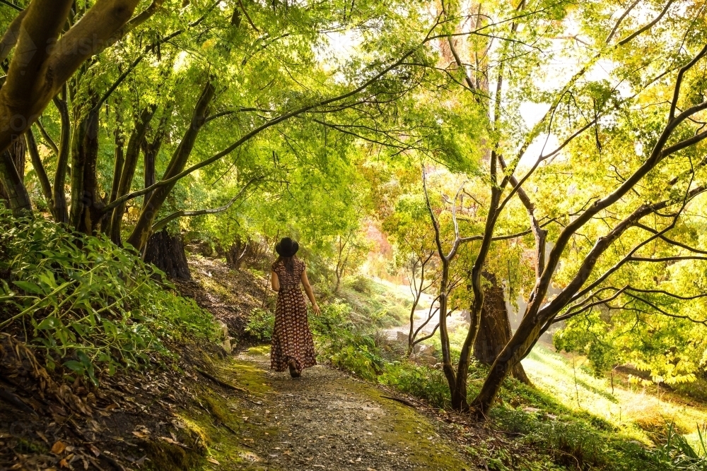 Female in dress walking through autumn garden - Australian Stock Image