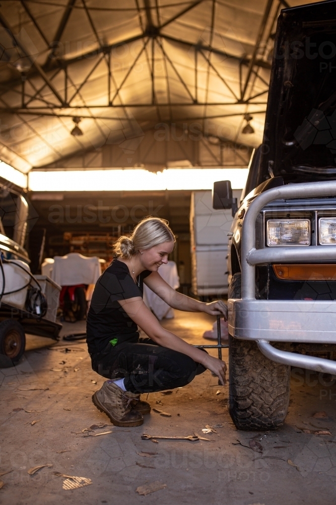 Female mechanic working on car tyres in an auto garage workshop - Australian Stock Image
