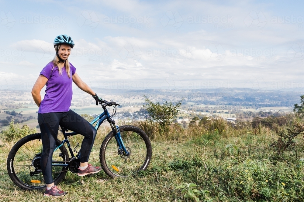 Female mountain bike rider smiling with bike - Australian Stock Image