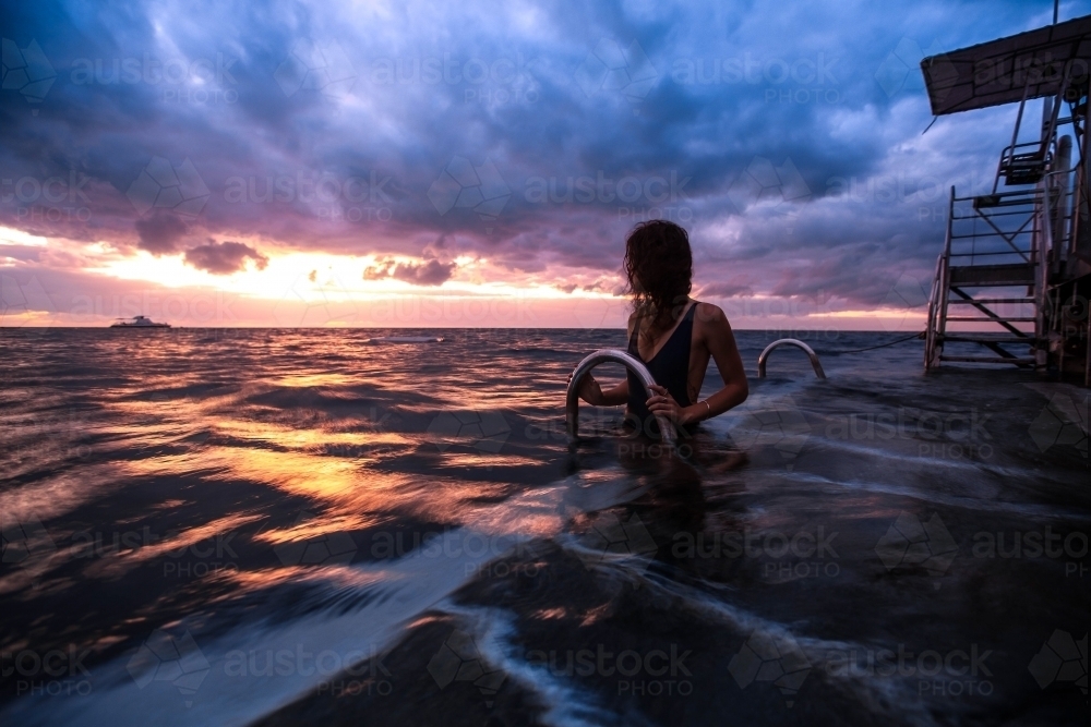 Female on pontoon in the ocean at Sunrise - Australian Stock Image