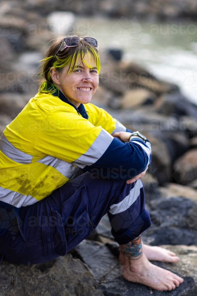 female outdoor worker wearing hi-vis work clothes relaxing with bare feet - Australian Stock Image