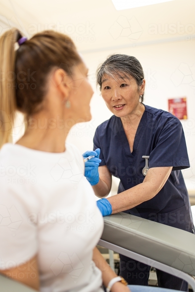Image of Female patient getting an injection on the arm by a female ...