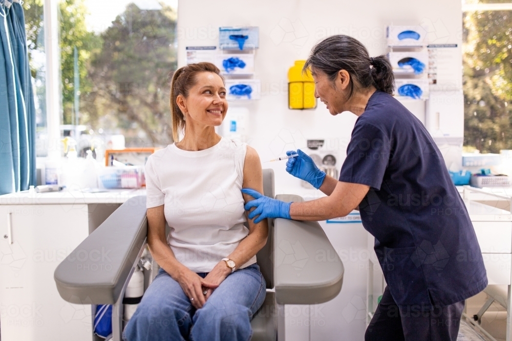Image of Female patient getting an injection on the arm by a female ...