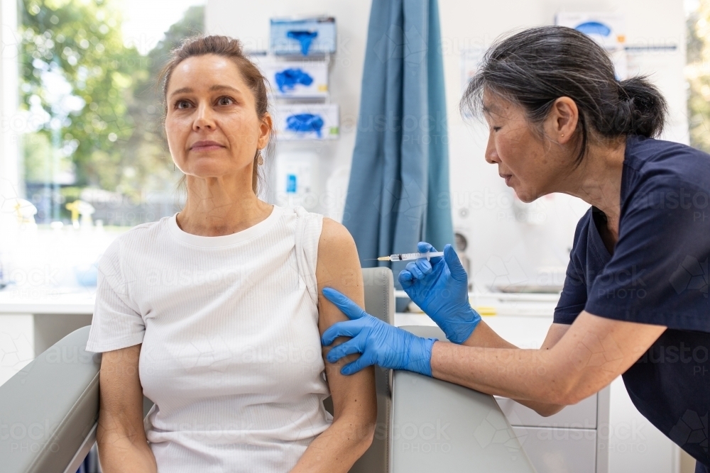 Image of Female patient getting an injection on the arm by a female ...