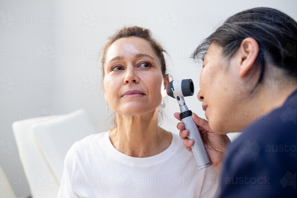 Image of Female patient having her ears checked by a female nurse using ...