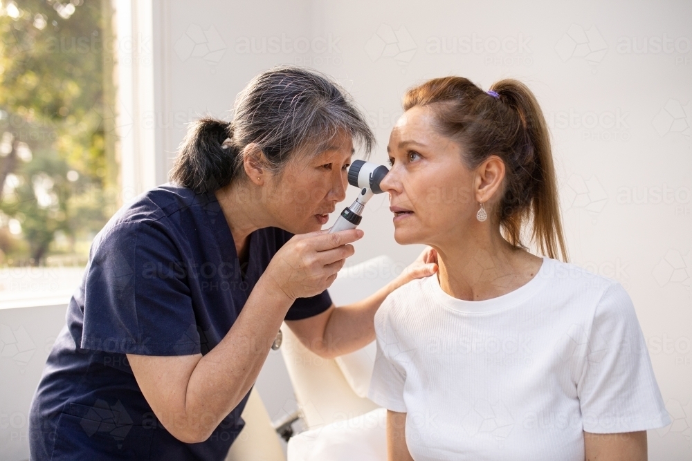 Image of Female patient having her ears checked by a female nurse using ...