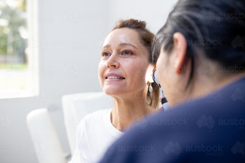 Image of Female patient having her ears checked by a female nurse using ...