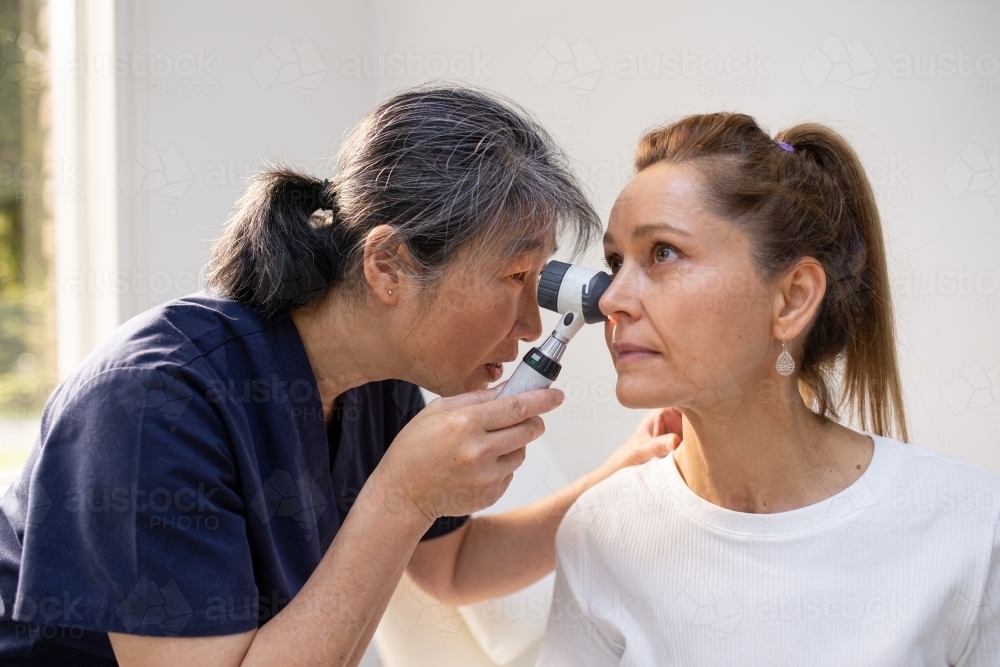 Female patient having her ears checked by a female nurse using an otoscope in the clinic - Australian Stock Image