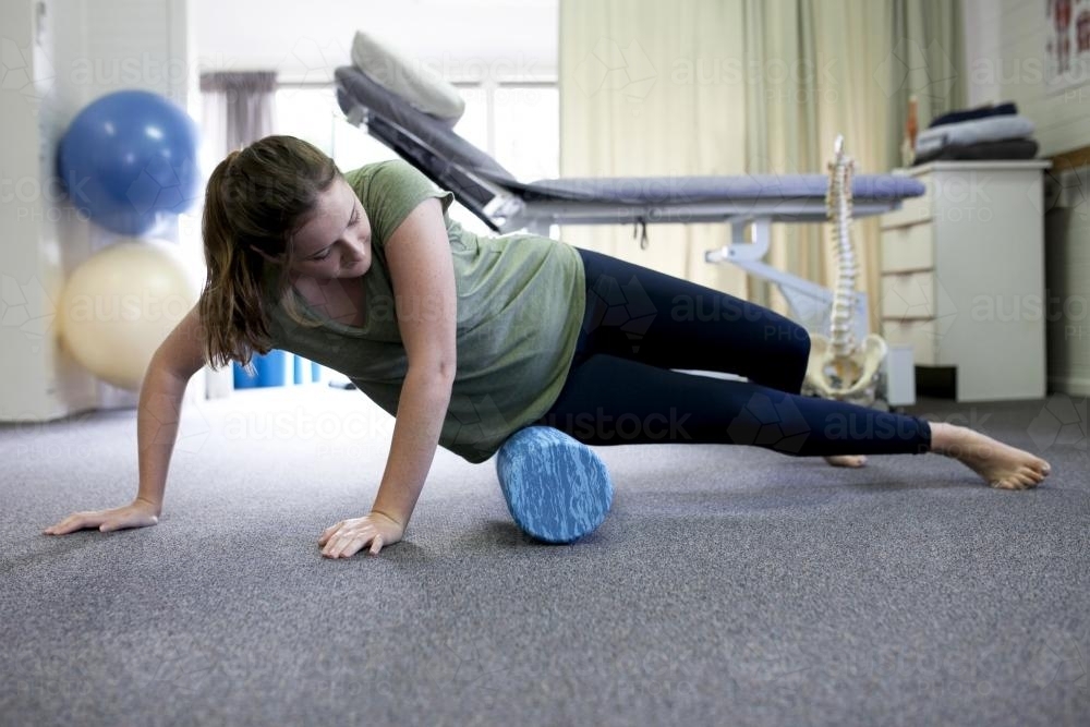 Female patient using a foam roller in a physio studio - Australian Stock Image