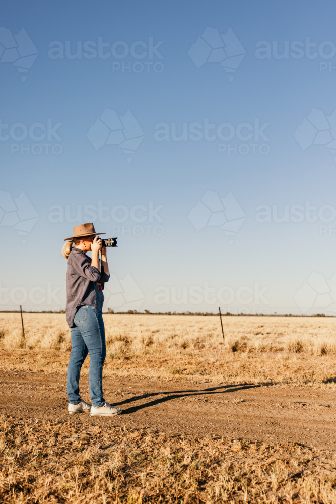 Female photographer using camera in paddock - Australian Stock Image