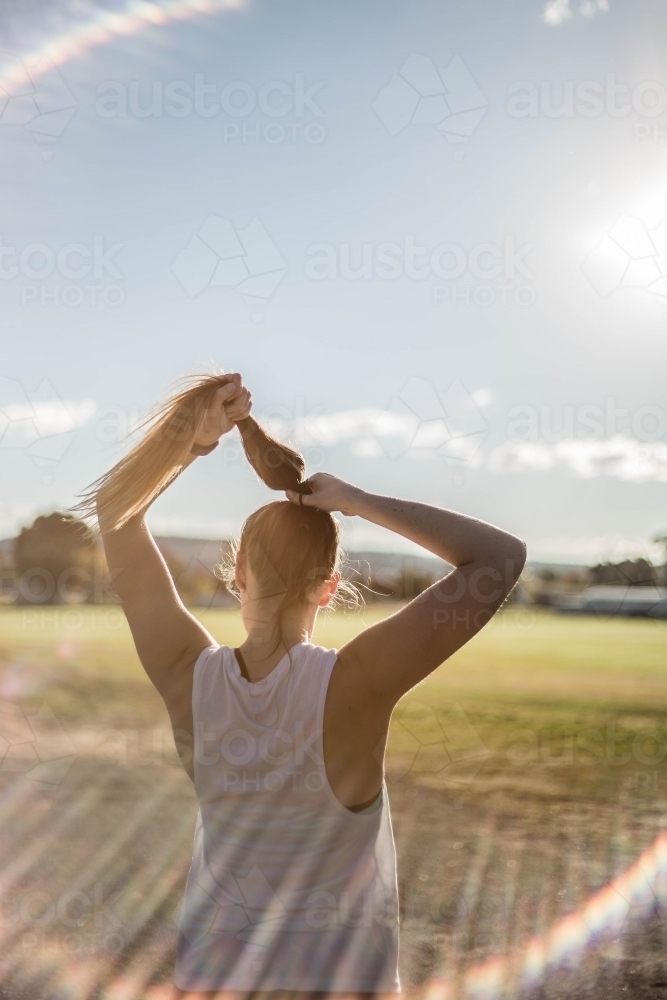 Female putting hair up outdoors - Australian Stock Image