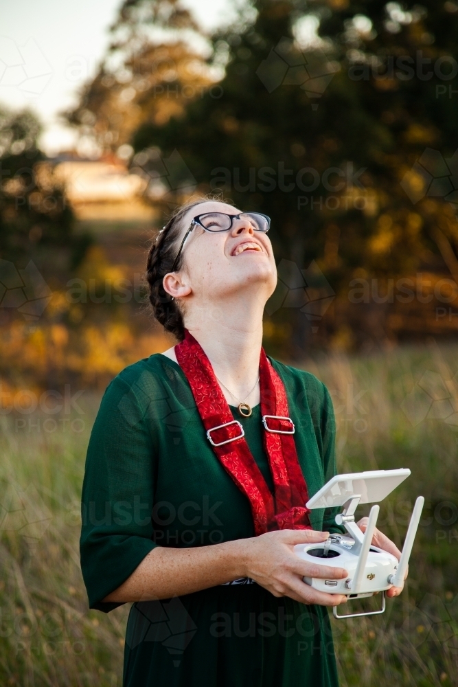 Female RPA pilot using a controller to fly a drone in rural area - Australian Stock Image