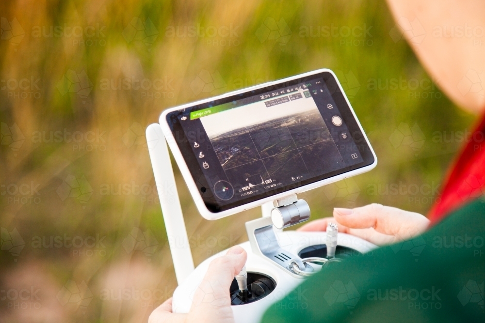 Female RPA pilot using a controller to fly a drone in rural area - Australian Stock Image