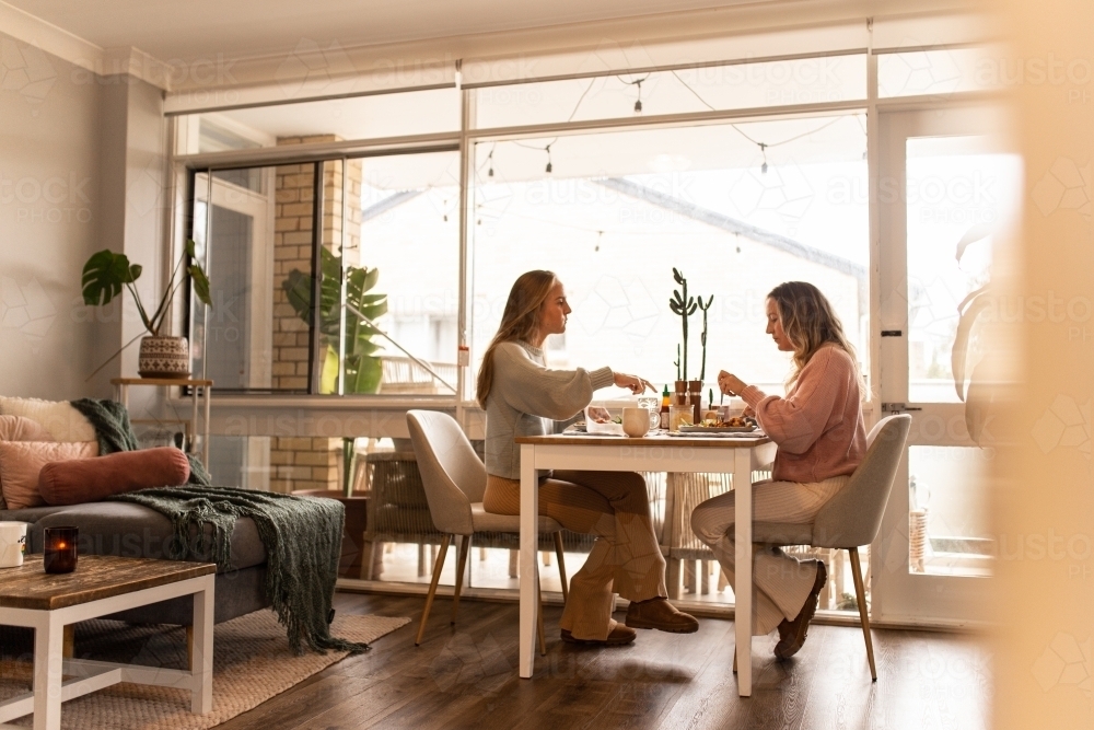 Female same sex couple eating a meal together at home - Australian Stock Image