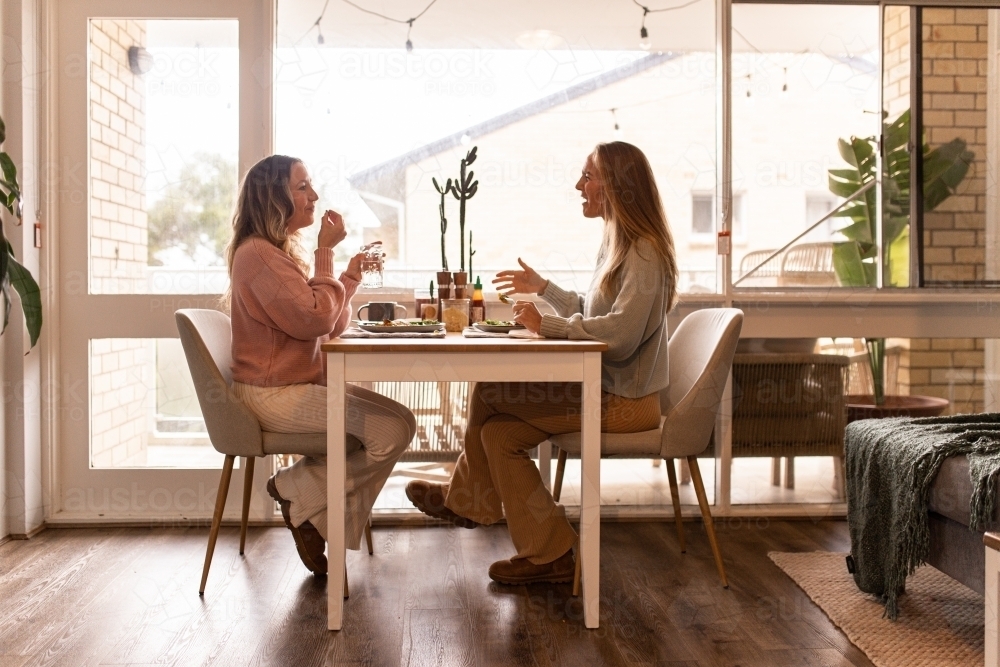 Female same sex couple eating a meal together at home - Australian Stock Image