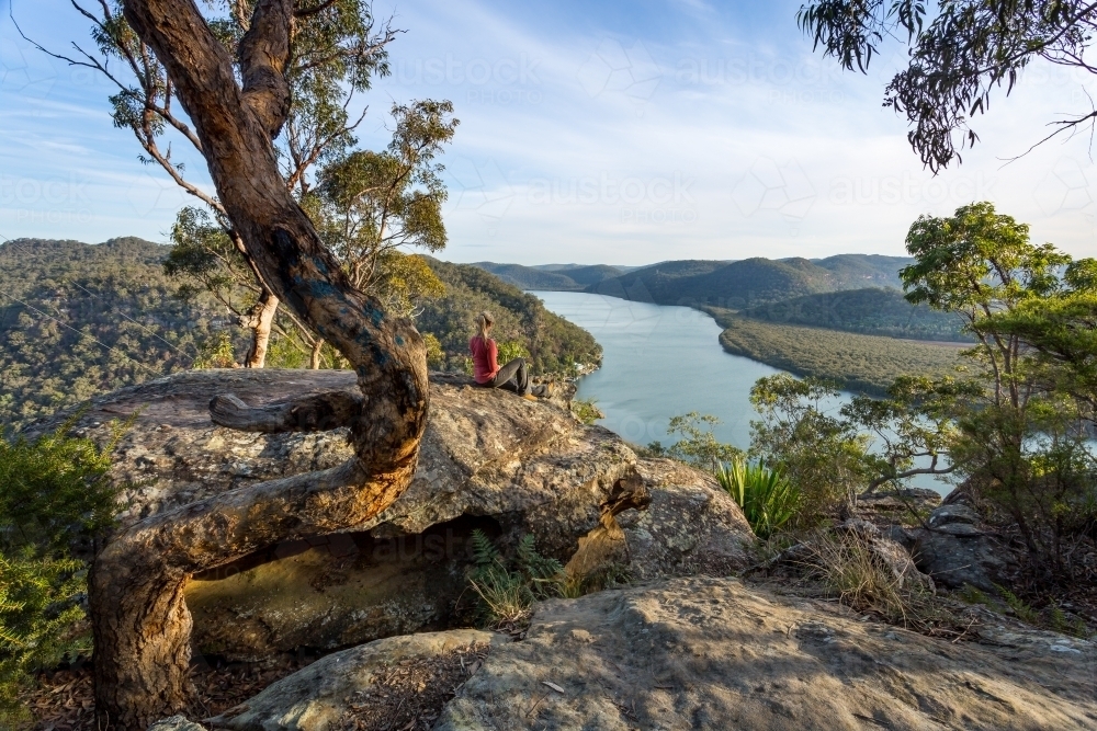 Female sitting on a large rock relaxing in afternoon dappled light the Australian bushland with view : Austockphoto Female sitting on a large rock relaxing in afternoon dappled light the Australian bushland with view - Australian Stock Image