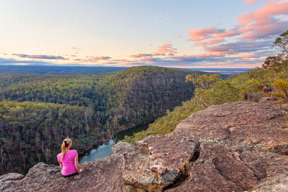 Female sitting on a rocky cliff with views over the Nepean Gorge and Blue Mountains, Australia - Australian Stock Image