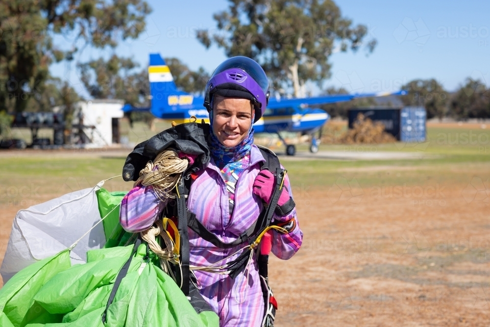 female skydiver hauling parachute back to clubhouse after a successful jump - Australian Stock Image