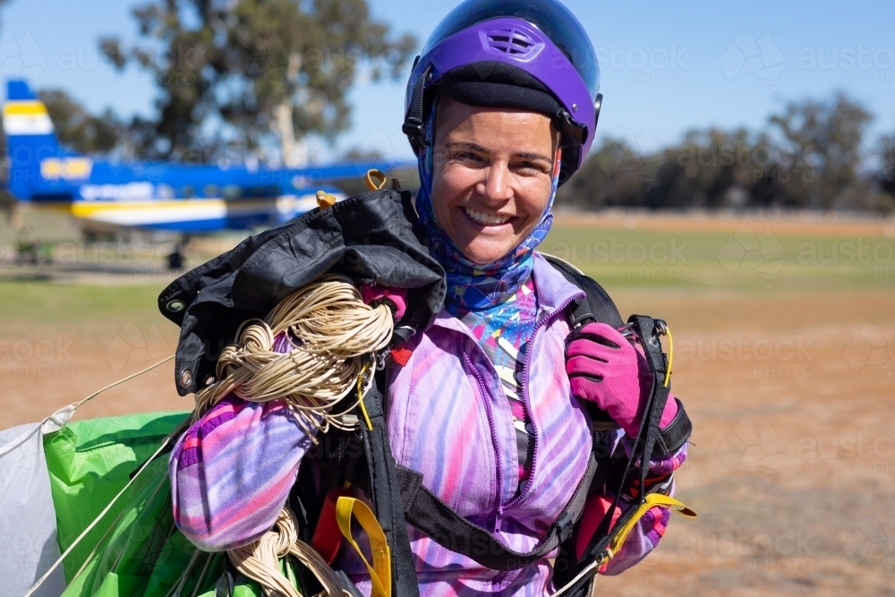 female skydiver walking back from drop zone after a jump - Australian Stock Image