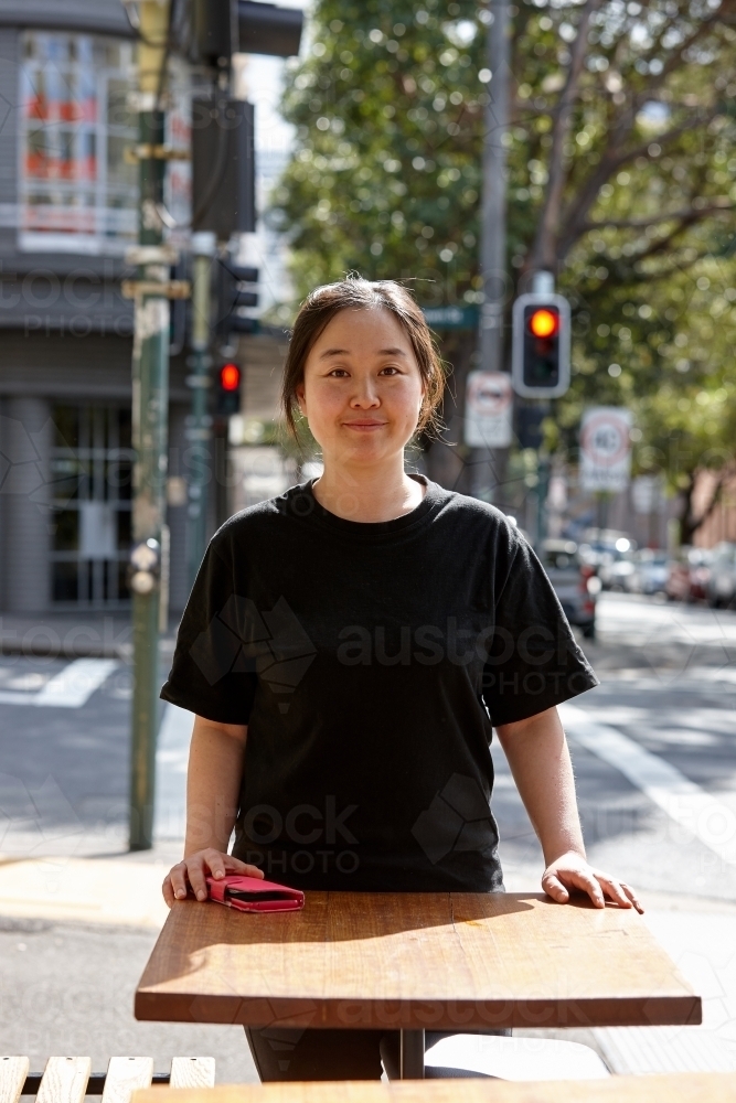 Female small business owner standing outside of cafe - Australian Stock Image