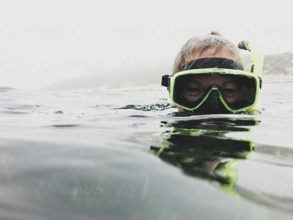 Female Snorkelers head  above water looking at camera on misty morning - Australian Stock Image