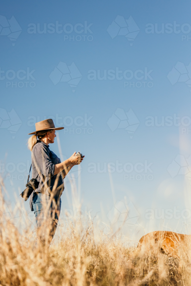 Female standing holding drone controller looking to sky - Australian Stock Image