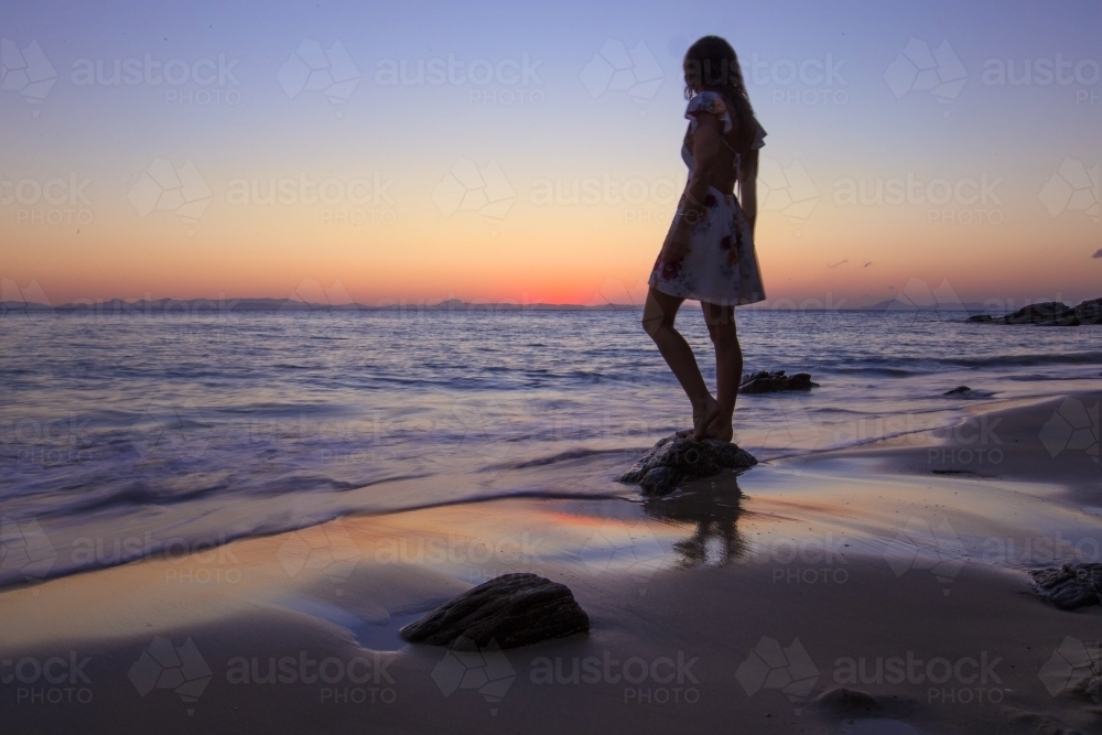 Female standing on Rock at the beach at Sunset - Australian Stock Image