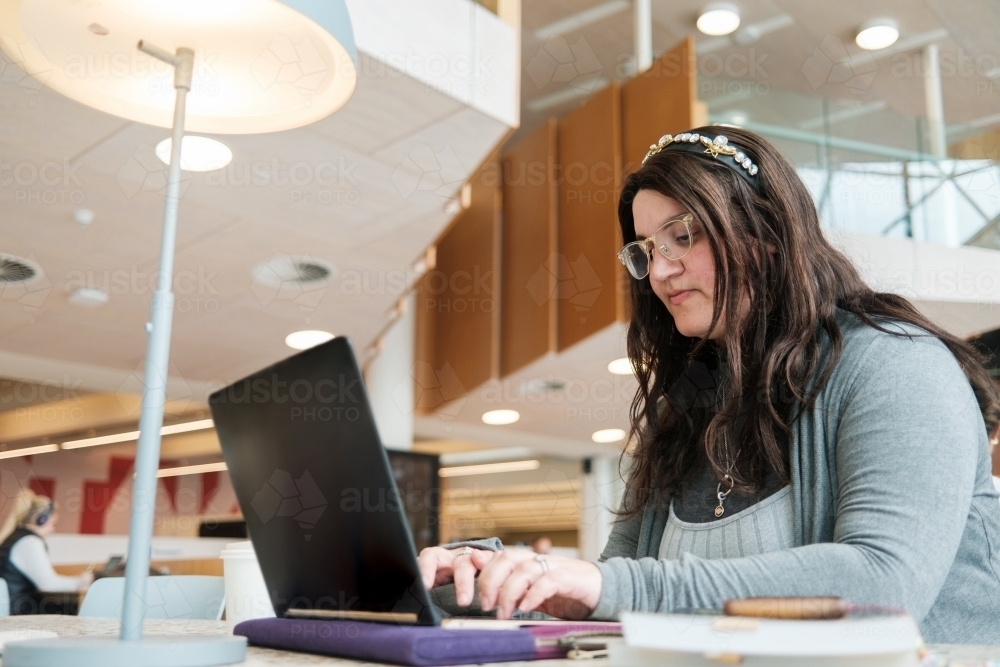 Female Student Typing on Laptop Indoors - Australian Stock Image