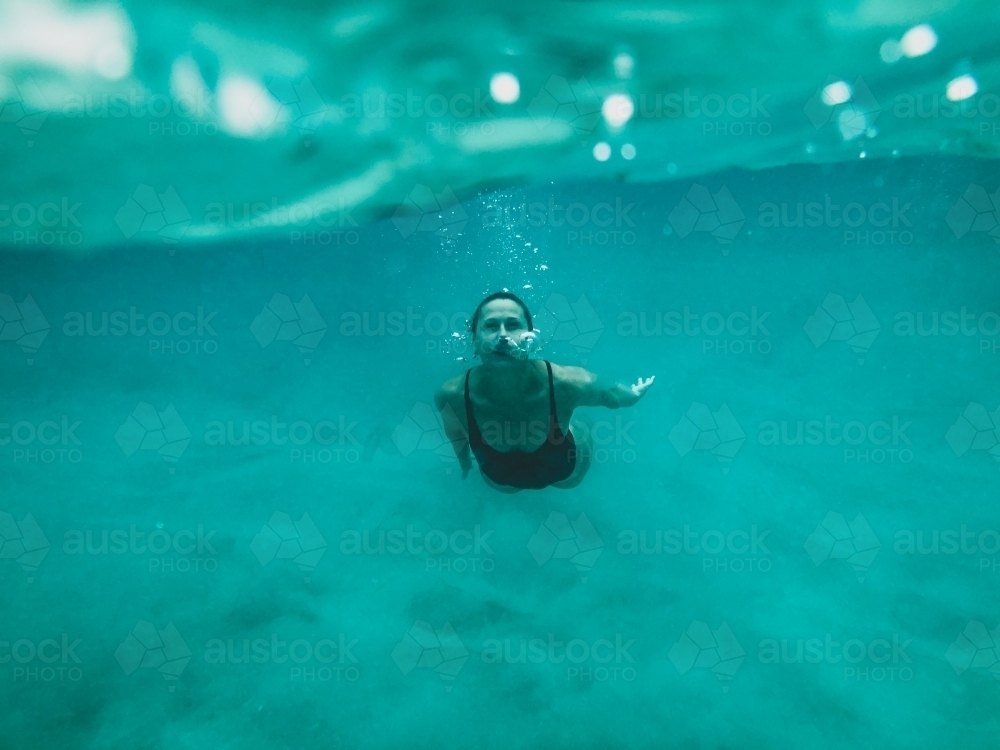 Female swimming underwater in the ocean bubbles coming from nose - Australian Stock Image